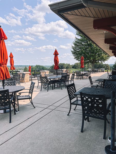 A patio with tables and chairs and umbrellas.