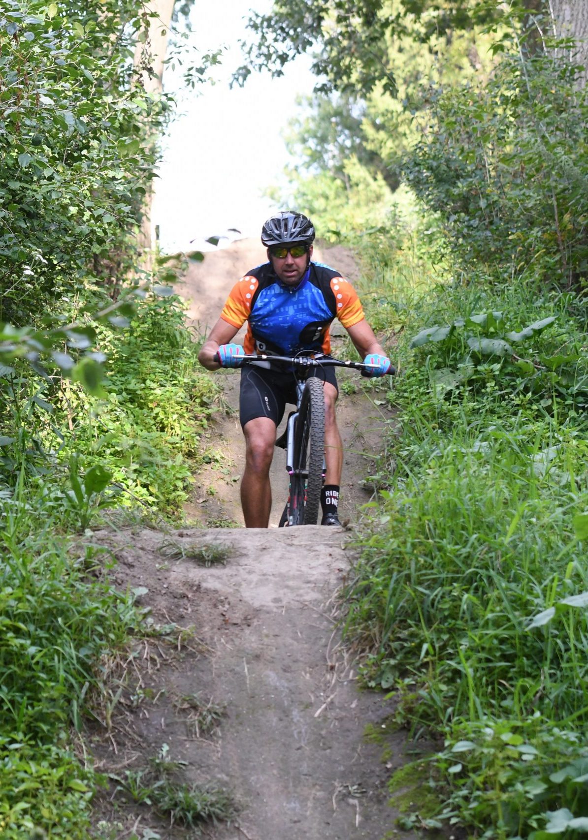 a man riding a bike down a dirt road.