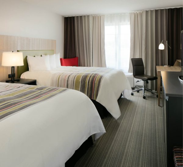 A hotel room with two beds and a desk.