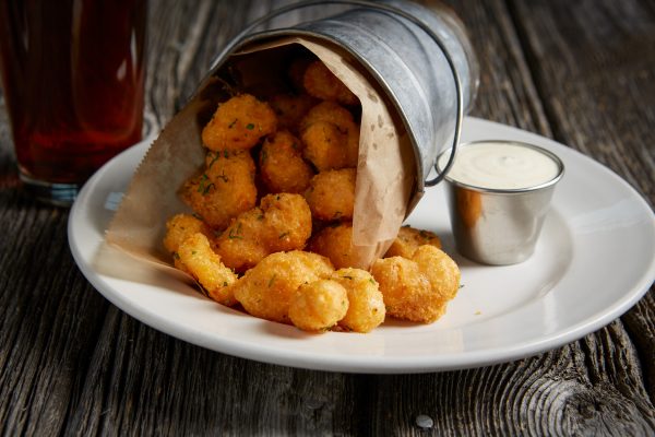 A white plate with fried calamari and dipping sauce.