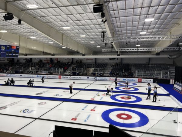 a group of people standing on top of a curling rink.