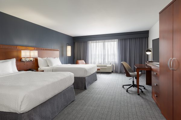 A hotel room with two beds and a desk.