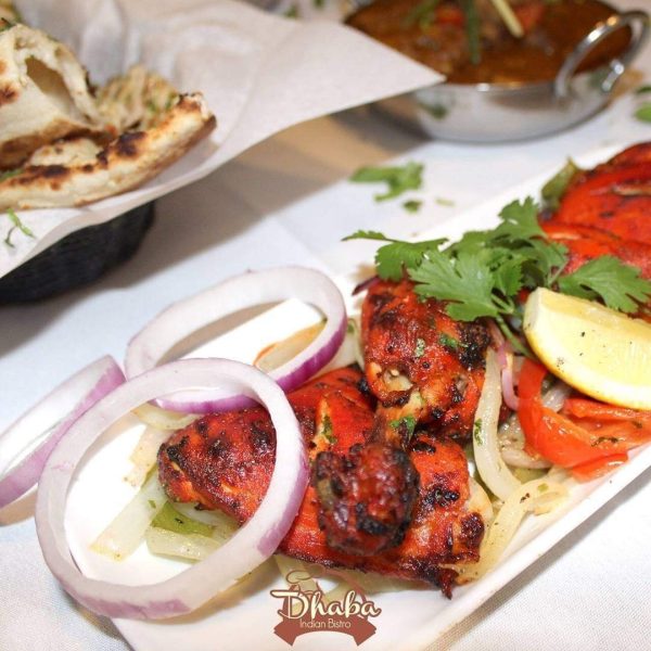 A plate of tikka masala and naan sitting on a table.