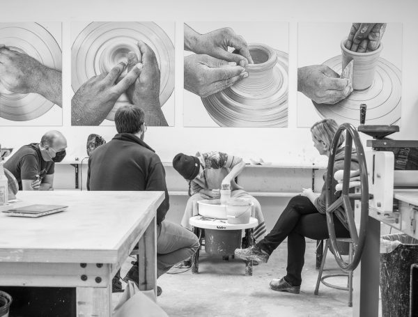 A black and white photo of people working in a pottery studio.