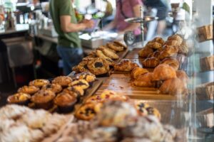 a bakery counter filled with pastries and people in the background