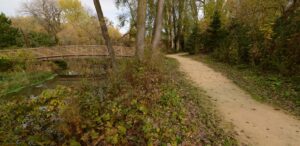 a wooden bridge over a small stream in a park