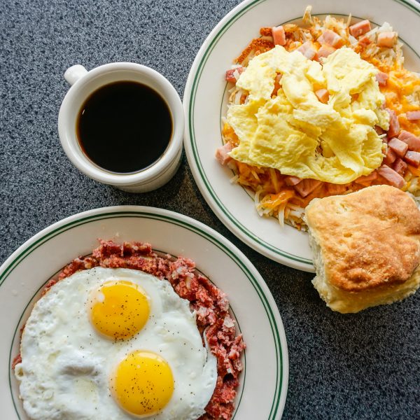Two plates with eggs, biscuits and coffee.