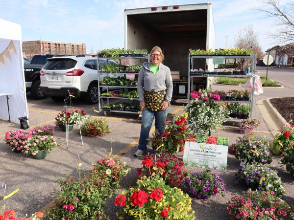a woman standing next to a bunch of flowers.