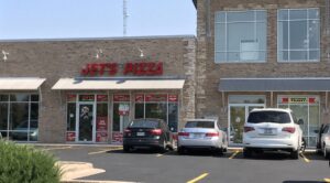 a pizza restaurant with cars parked in front of it
