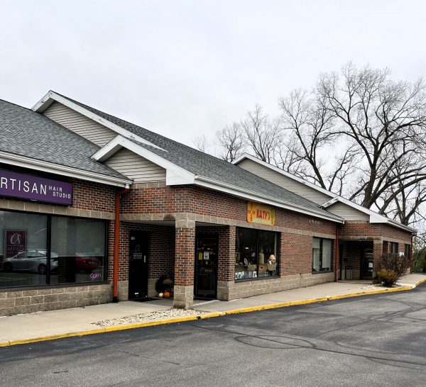 A small brick strip mall with a hair studio and a restaurant. The sky is overcast and trees are bare.