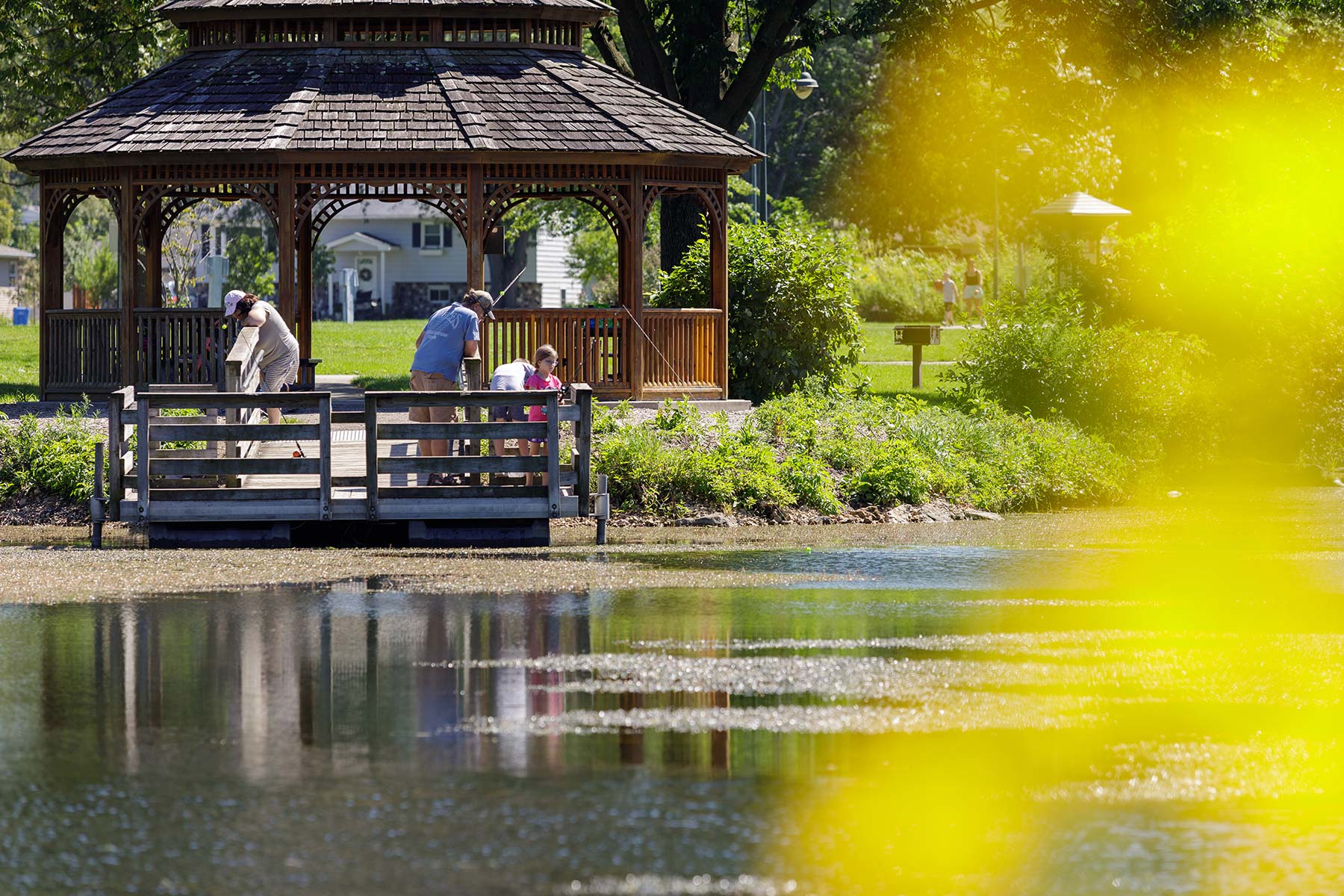 people are sitting on a bench near a lake