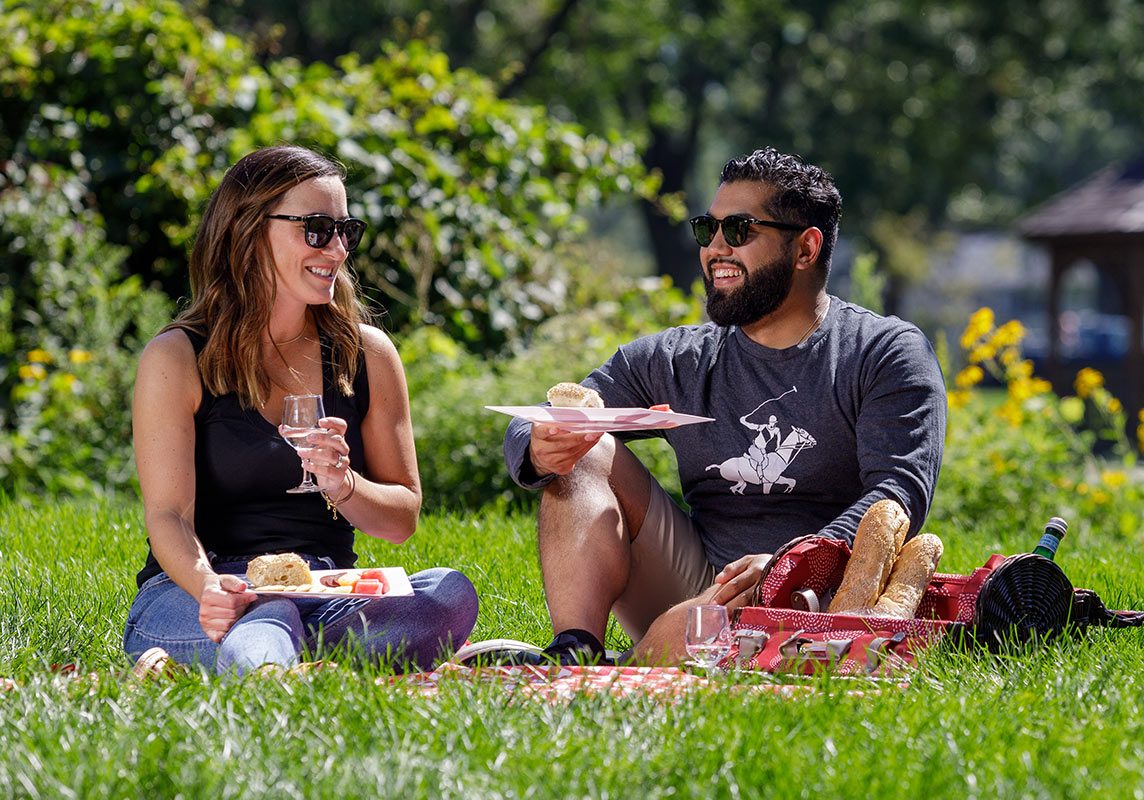 a man and a woman sitting on the grass eating food