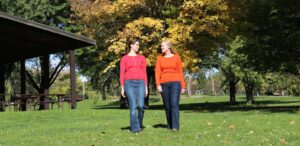 a couple of women standing on top of a lush green field