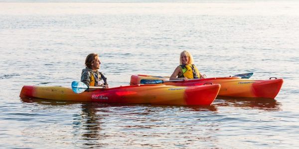 two people in a red and yellow kayak in the water.
