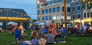 a group of people sitting on top of a lush green field