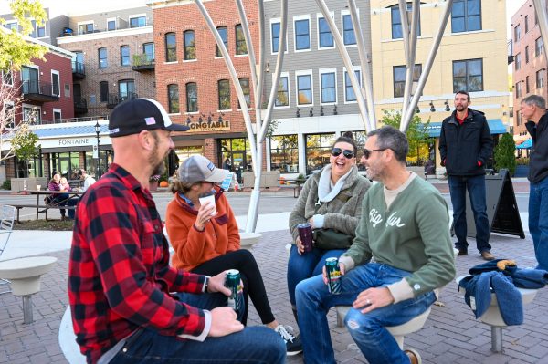 A group of people sitting on a bench in a city square.
