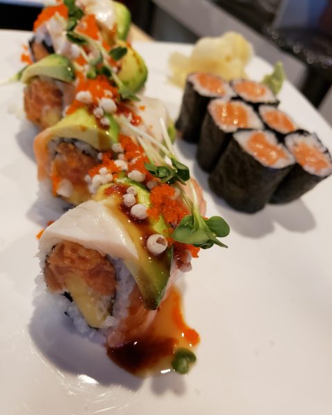 A white plate with sushi and vegetables on it.