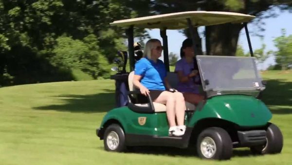 a man and a woman riding on a green golf cart